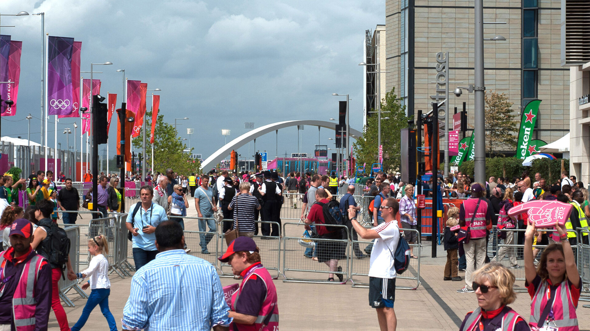 People gathering in Olympic park with Stratford Bridge 20 arch in the distance