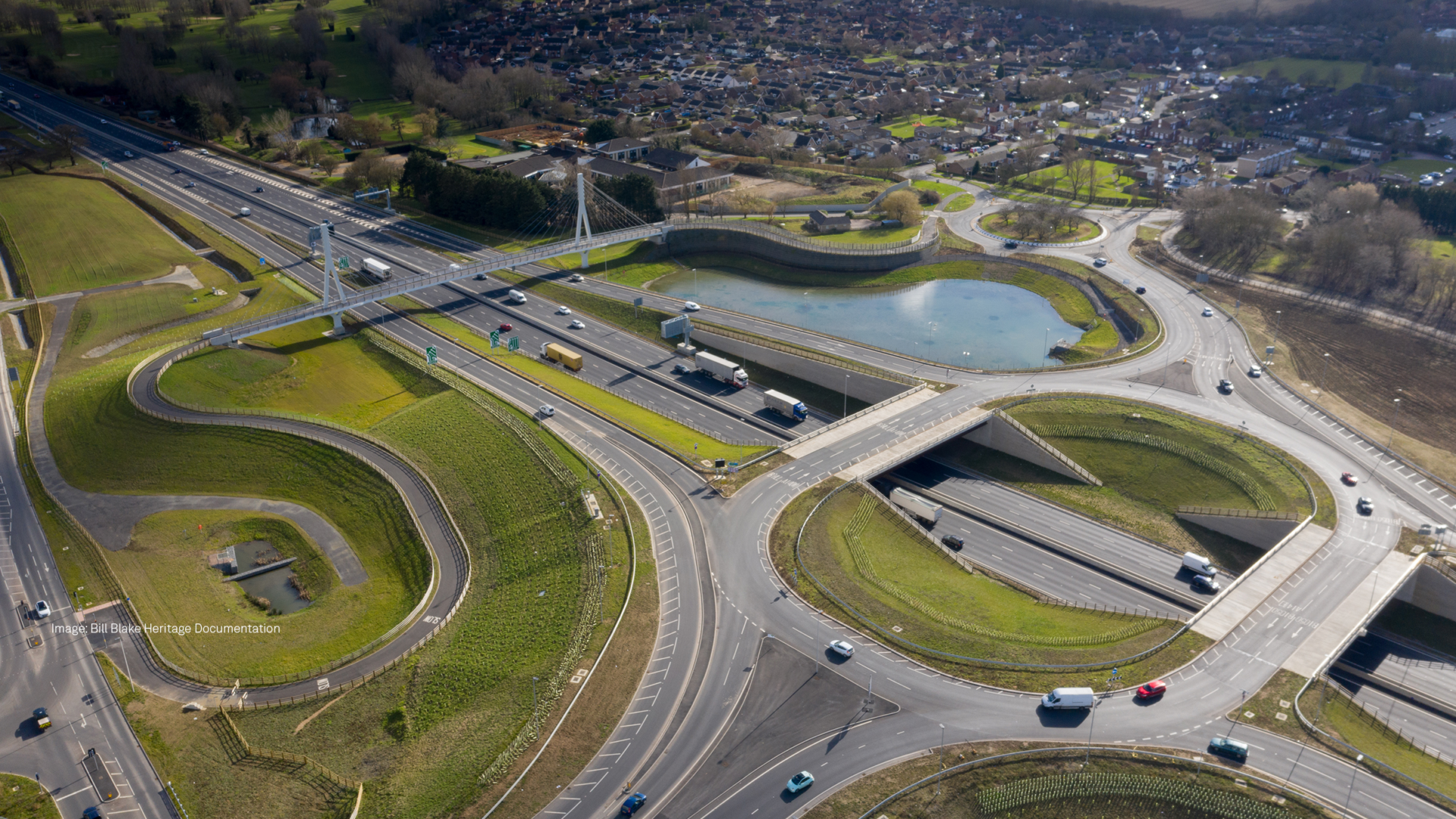 Multiple roads, roundabouts and a pedestrian bridge seen from above