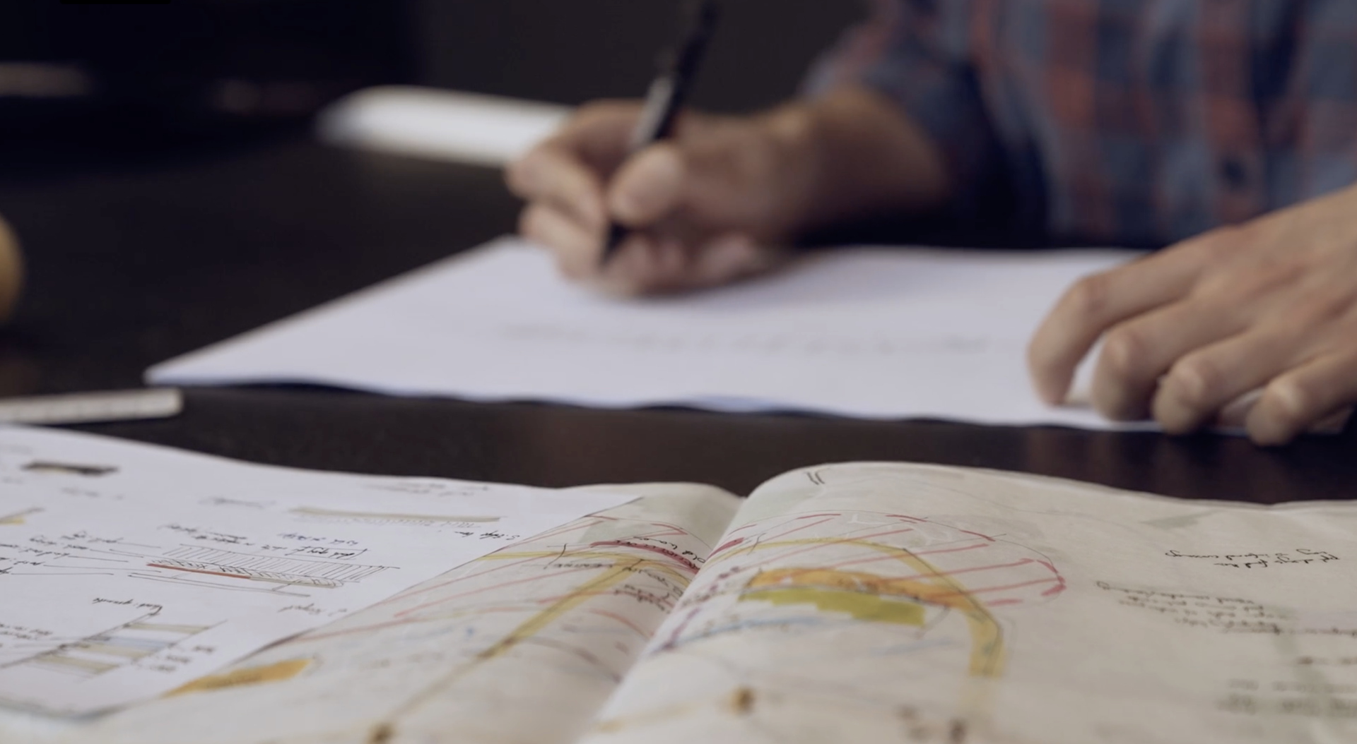 Closeup of architectural drawings with hands holding a pen