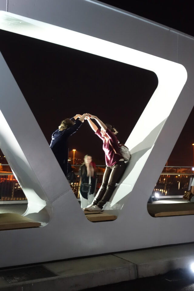 People joining hands in archway of bridge