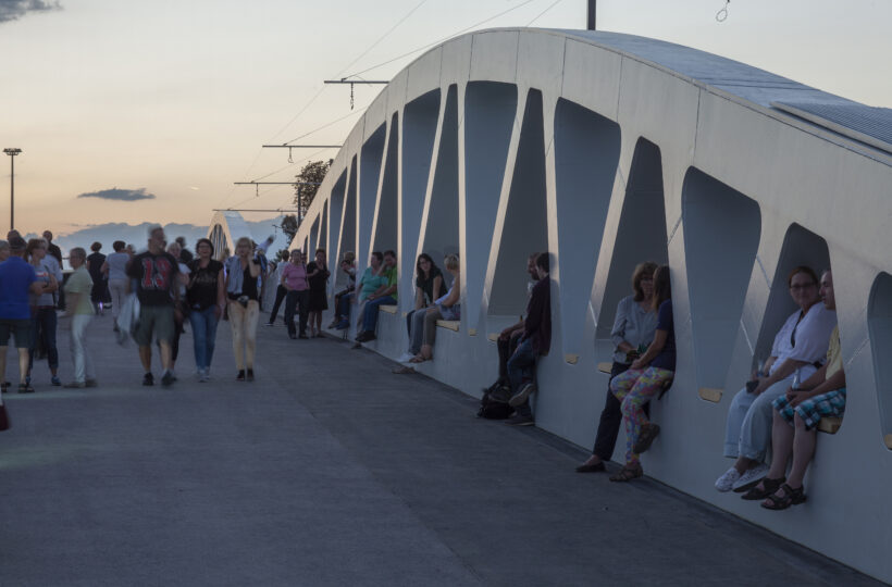 People and walking and sitting on Kienlesberg bridge with sunset backdrop