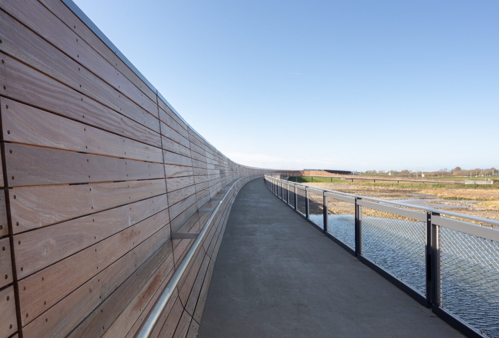 Close view of the timber walkway and parapet looking out across the river and fields in distance