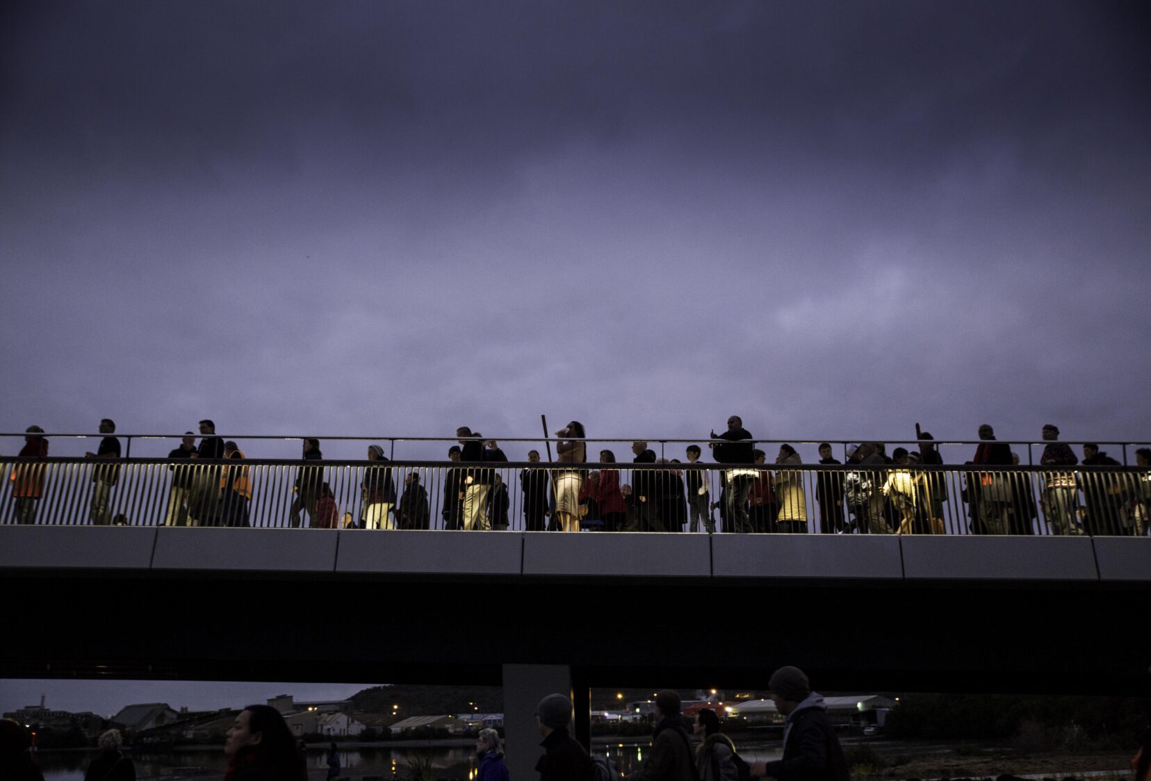 Silhouettes of people against  a cloud sky on the bridge at the opening ceremony.