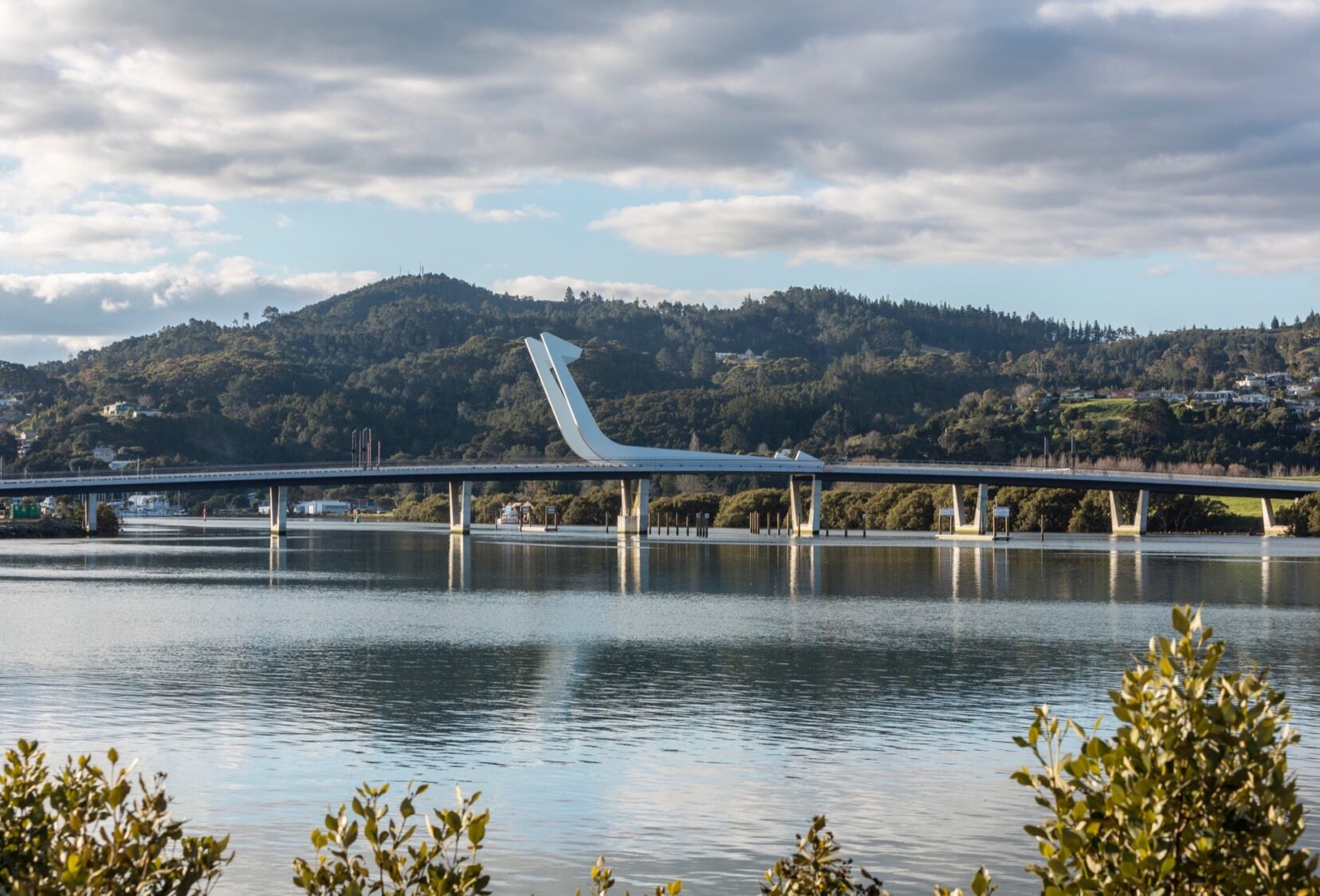 Closed Lower Hatea bridge in distance with hills in background and cloudy sky