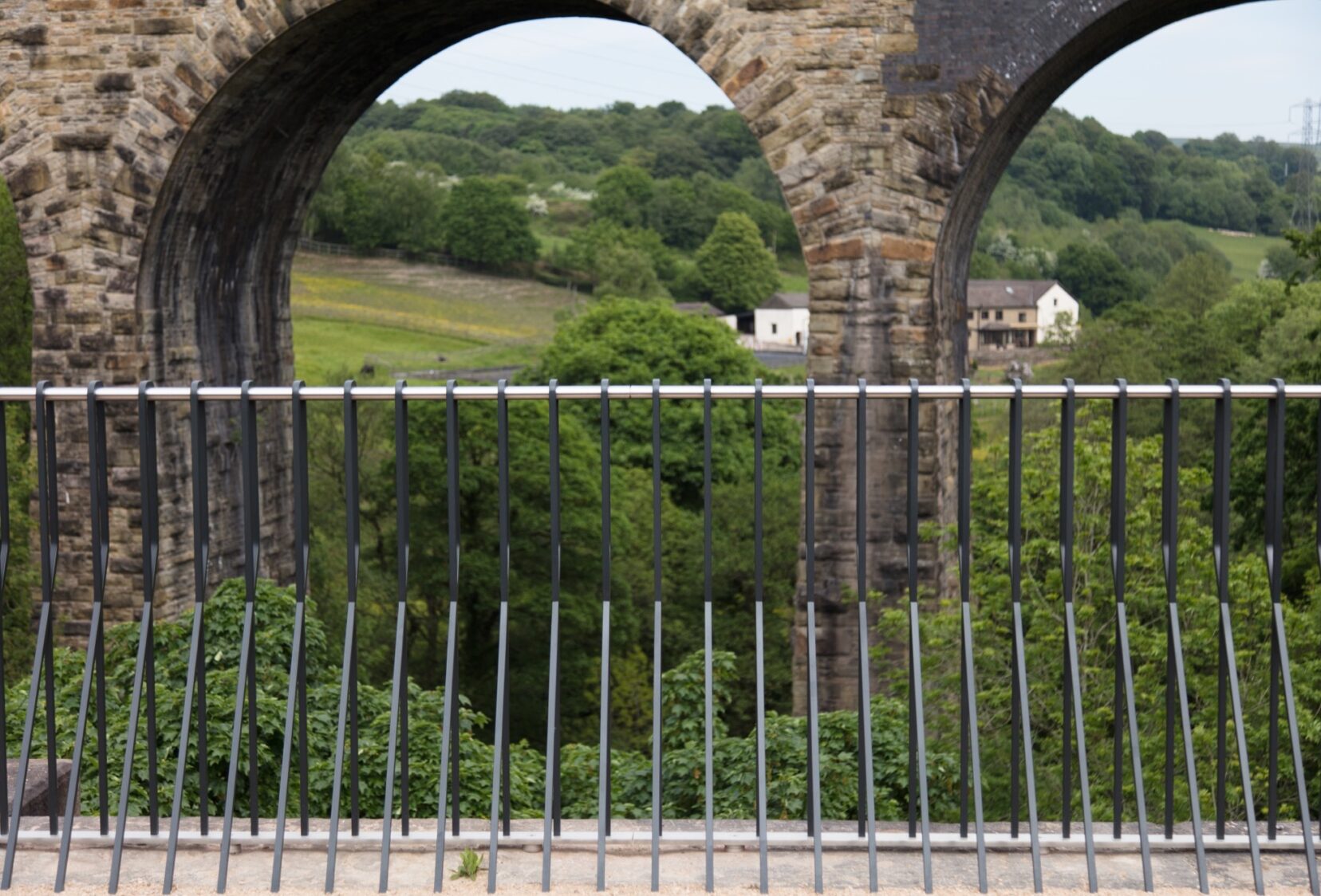 Looking directly at the parapet from on the Aqueduct looking at bridge, trees and houses behind