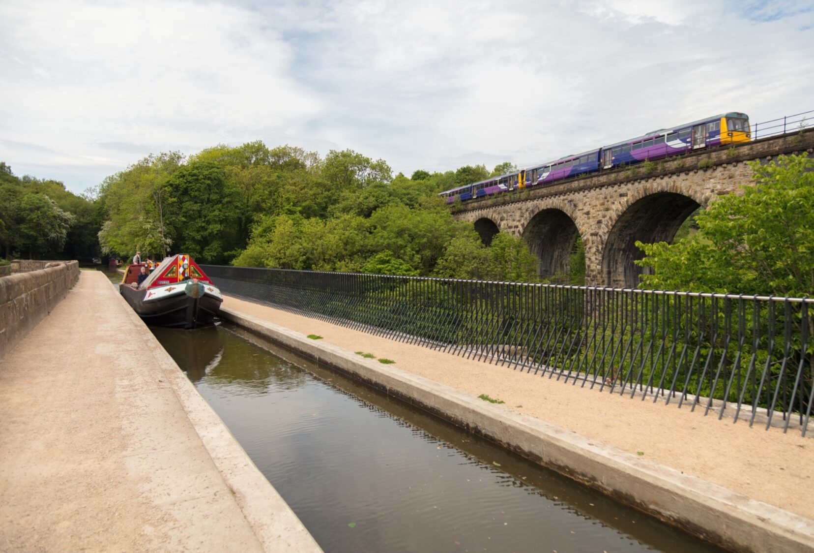 Canal boat on Aqueduct and train on Bridge next to Aqueduct with parapet in between