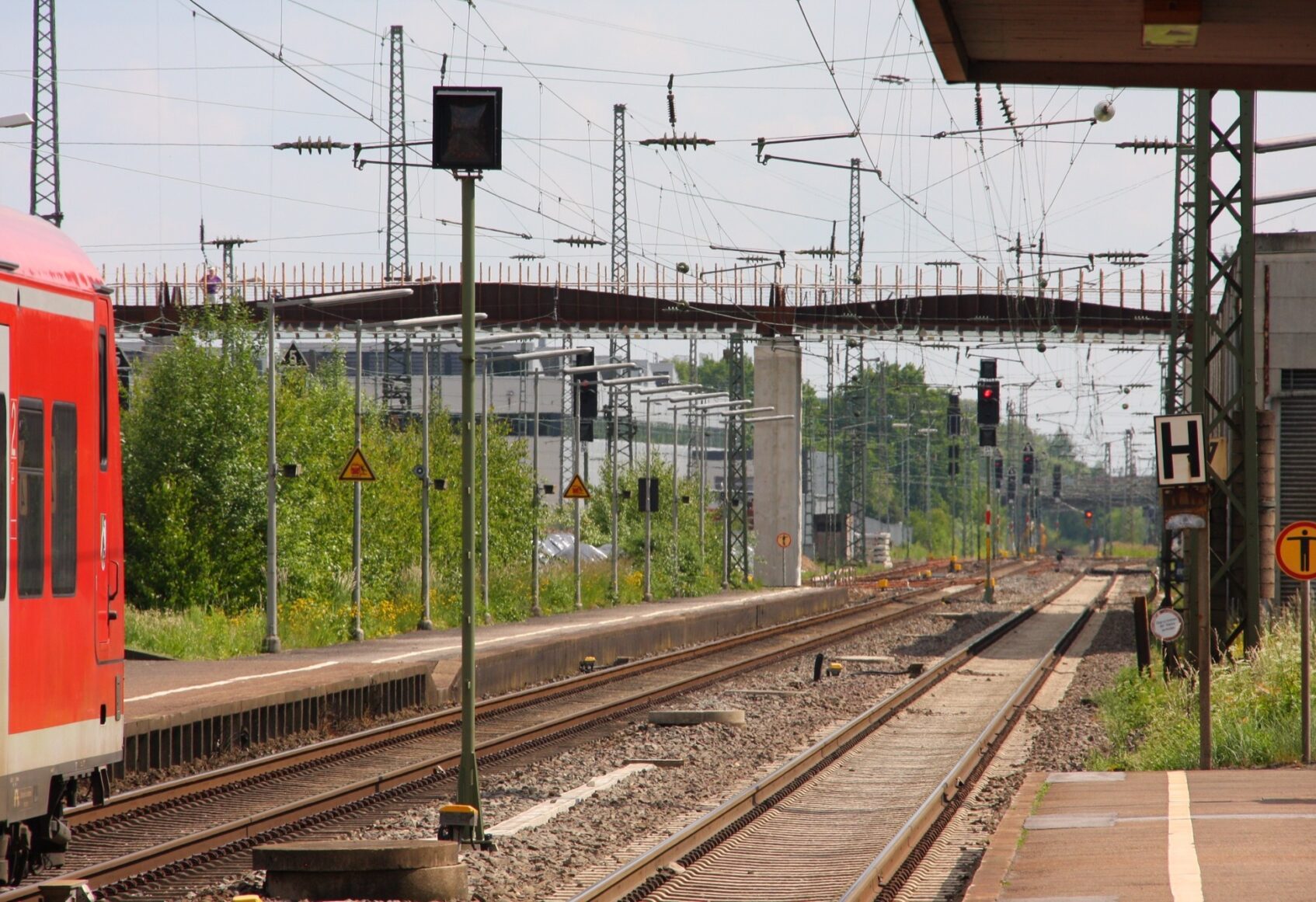 Train on left approaching underneath of bridge in distance